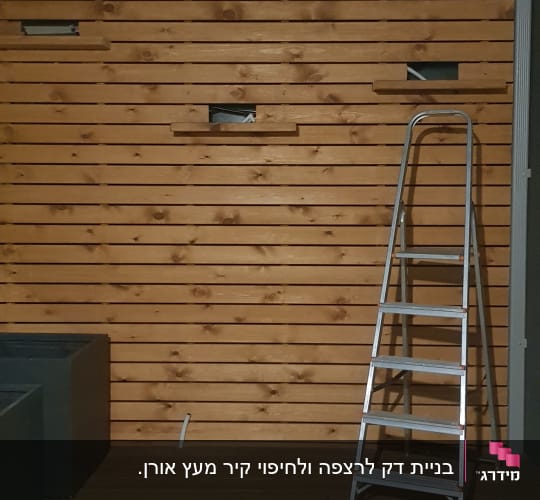 קיר עץ עם סולם מתכת ומקדחה על הרצפה